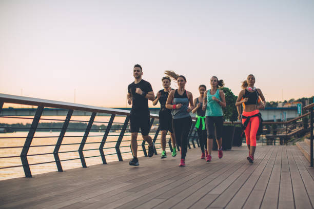 Young men and women running on city streets. They are wearing sport clothing.